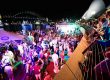Waterfront night party with colorful lights and Sydney Harbour landmarks.