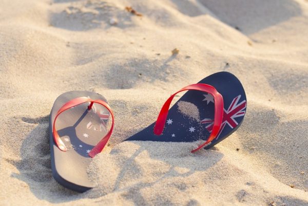 australianbeachestovisitin2016 A pair of flip-flops with a design of the Australian flag on a sandy beach.
