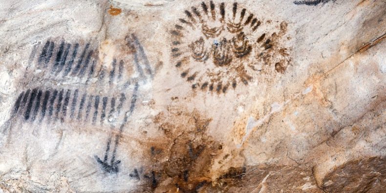 placestoseeaboriginalart Aboriginal rock art with ancient symbols painted on a cave wall.
