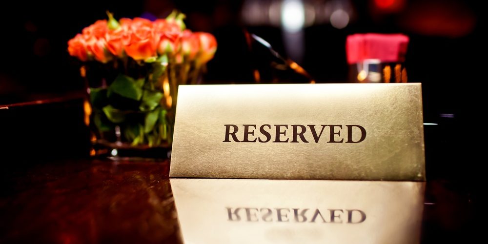 reserved A gold-colored tent card with the word 'RESERVED' is placed on a reflective table.
