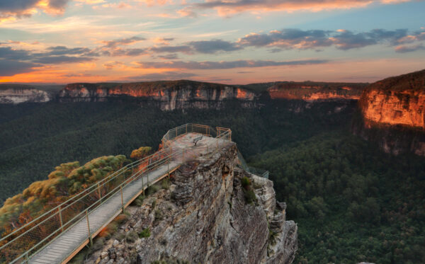 Pulpit Rock Blue Mountains Australia scenic views A lookout platform on a cliff overlooking a forested valley in the Blue Mountains at sunset.