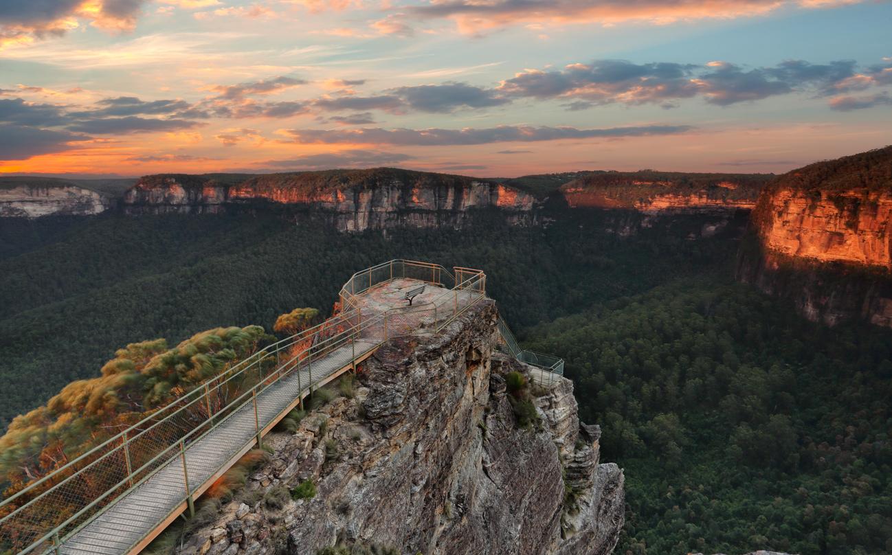 Pulpit Rock Blue Mountains Australia scenic views A lookout platform on a cliff overlooking a forested valley in the Blue Mountains at sunset.