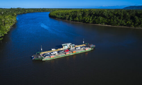 Daintree Discovery Centre Drone shot of Daintree Ferry with cars traveling on water.