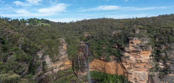 A beautiful waterfall cascades over a tall sandstone cliff in Australia's Blue Mountains national park.