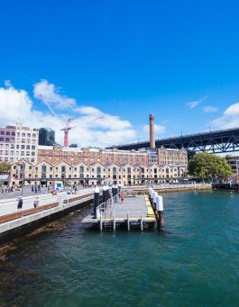 Sydney's Walsh Bay waterfront with historic buildings, a pier, and the Harbour Bridge.